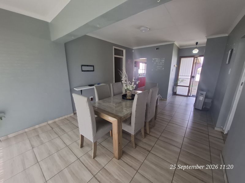 Open-plan dining area featuring neutral tiled flooring and direct access to the exterior through a sliding glass door.