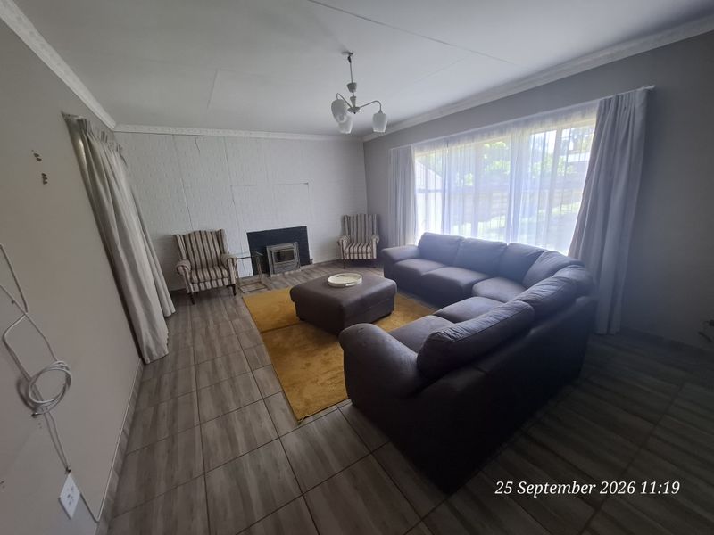 Spacious living room featuring tiled flooring, a built-in fireplace, and large windows allowing for natural light.