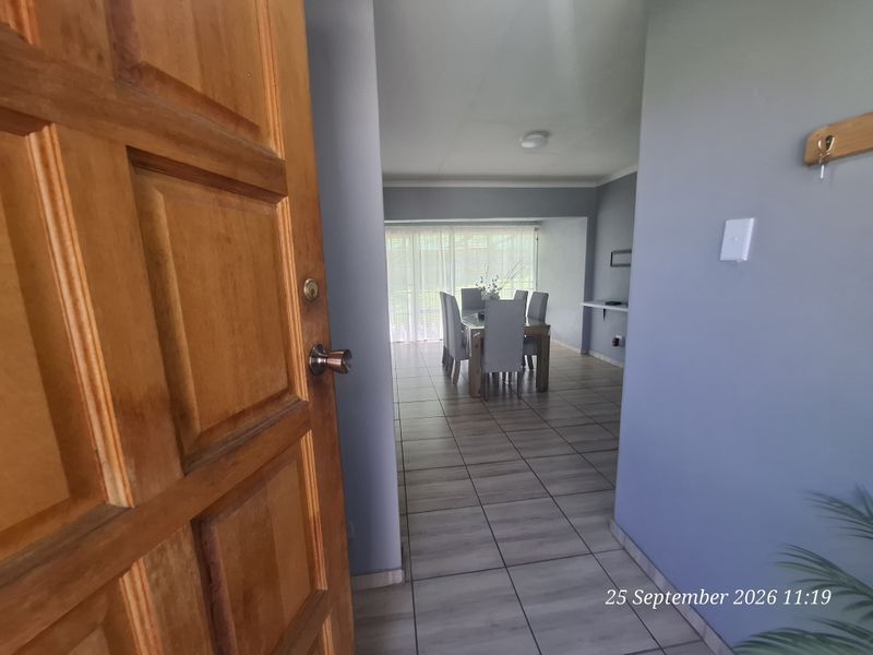 Entrance foyer leading into an open-plan dining area with tiled flooring and neutral wall finishes.