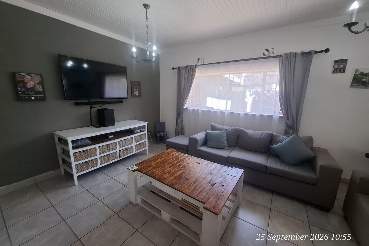 A comfortable living room featuring tiled flooring, a tongue and groove ceiling, and a neutral color palette, providing a functional and inviting space.