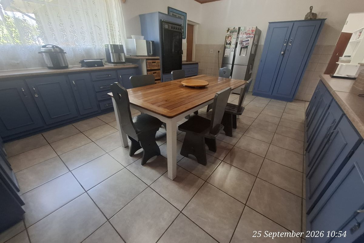 A spacious kitchen featuring blue built-in cabinetry, tiled flooring, and a timber ceiling, offering a functional layout with ample storage space.
