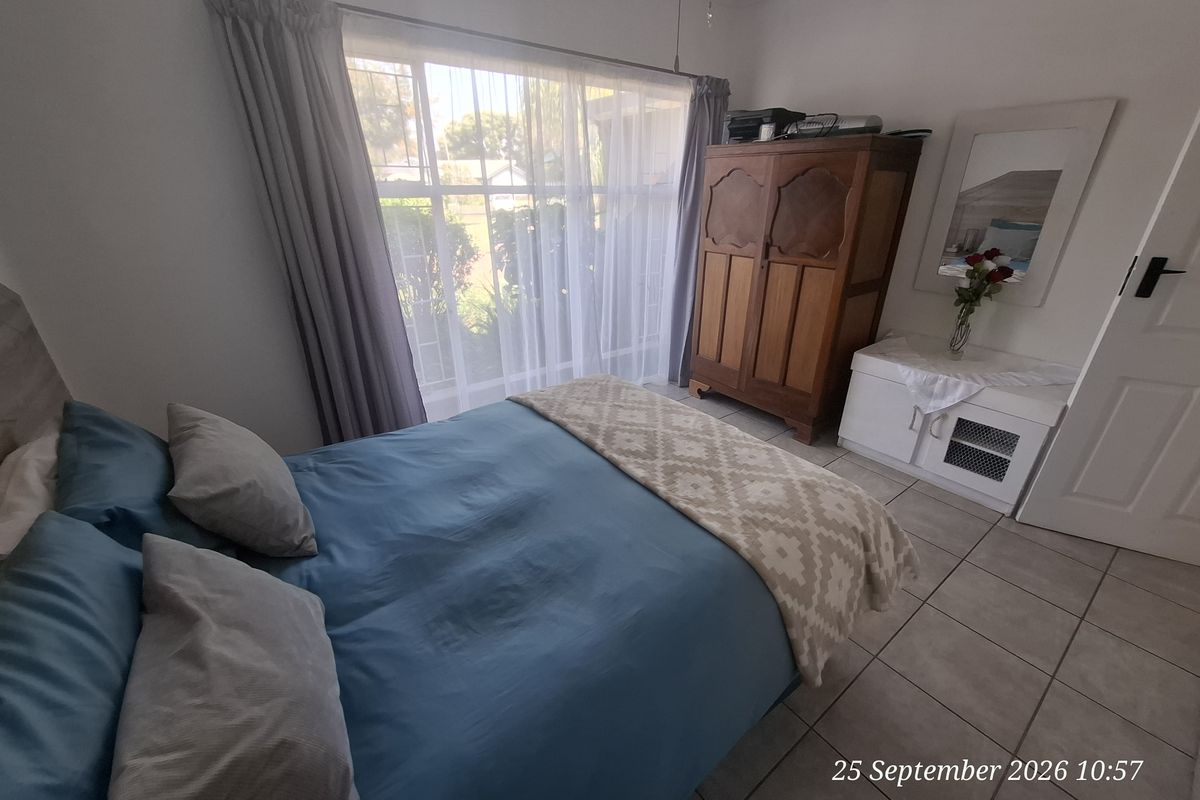 A functional bedroom featuring tiled flooring and a large window that allows for natural light.
