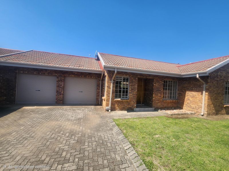 Front elevation of a face-brick townhouse featuring a double garage, paved driveway, and tiled roof.
