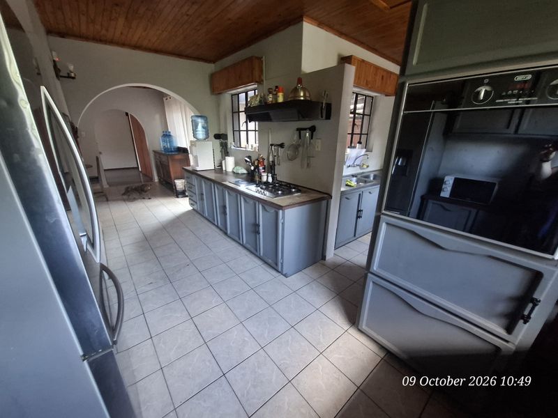 A functional kitchen featuring built-in cabinetry, a gas hob, and a built-in oven, complemented by tiled flooring and a timber ceiling.