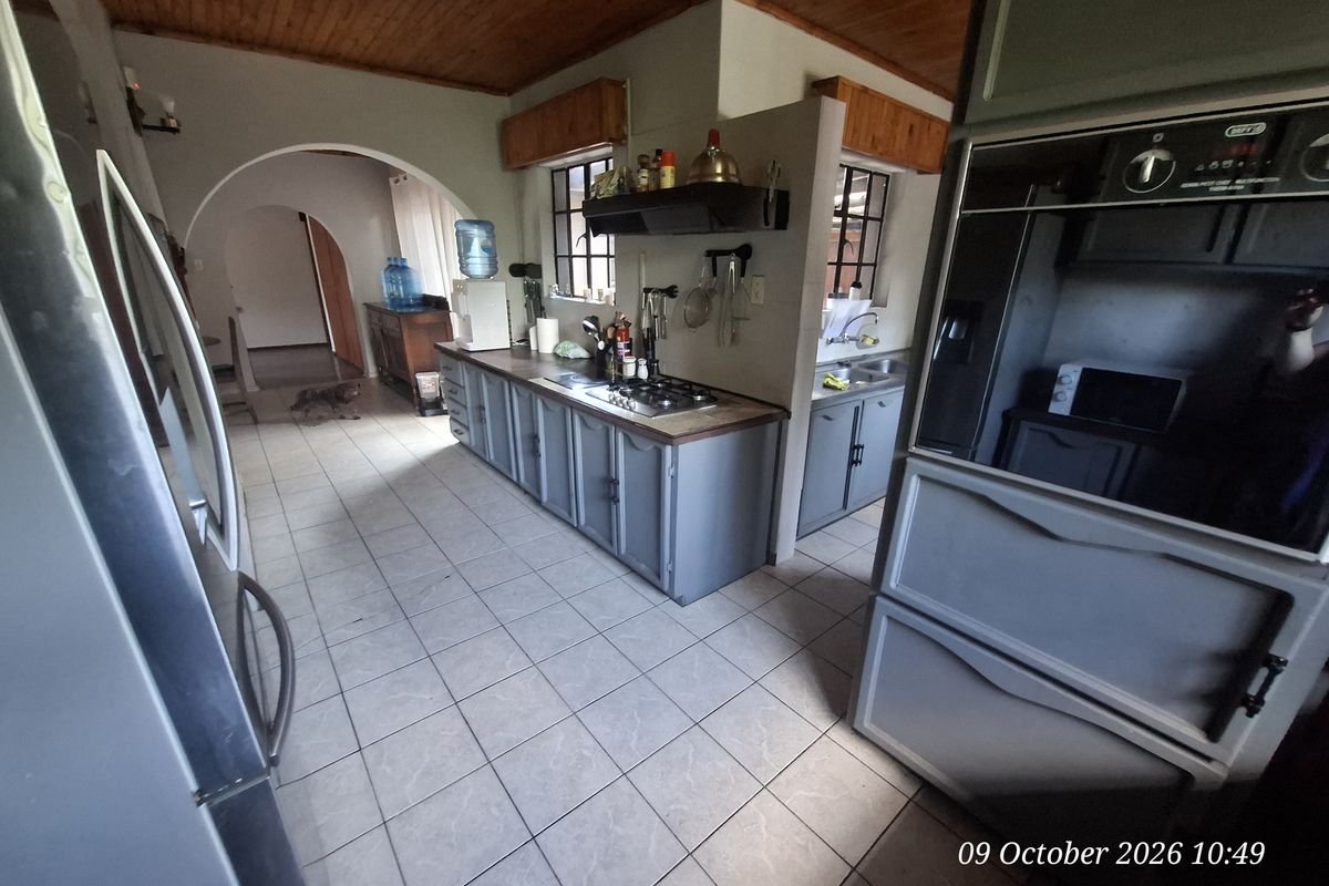 A functional kitchen featuring built-in cabinetry, a gas hob, and a built-in oven, complemented by tiled flooring and a timber ceiling.