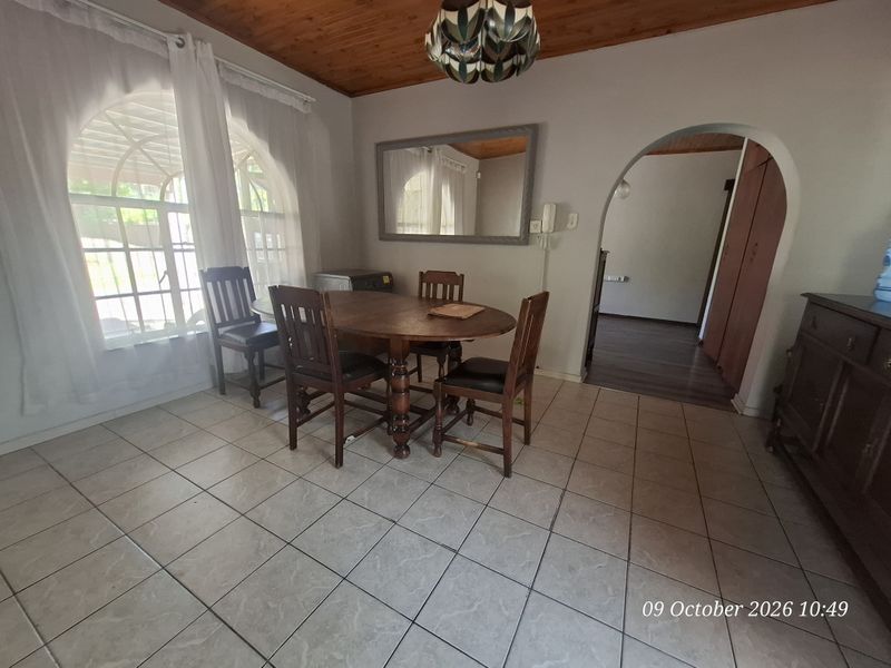 Dining room featuring tiled flooring, timber ceiling, and arched architectural details, providing a classic layout with access to adjacent living spaces.