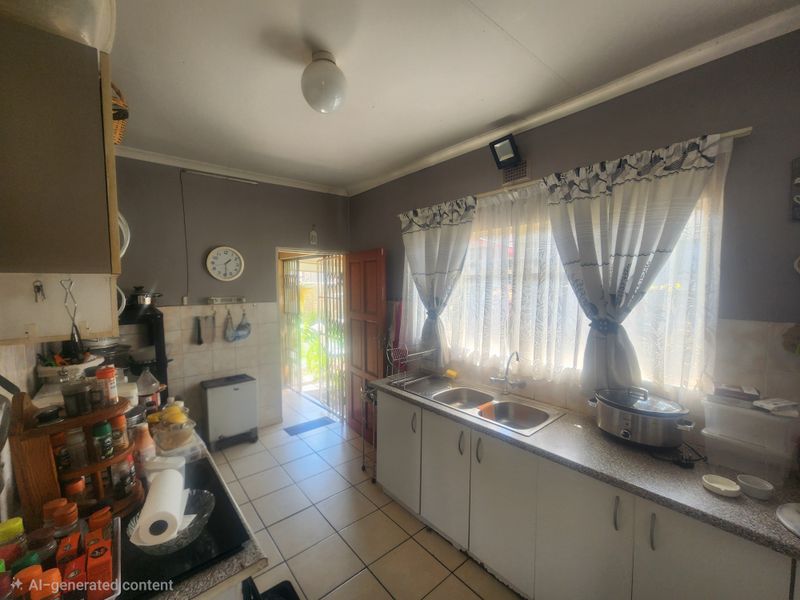 A functional kitchen featuring double bowl stainless steel sink, laminate countertops, and tiled flooring, with direct access to an exterior door.