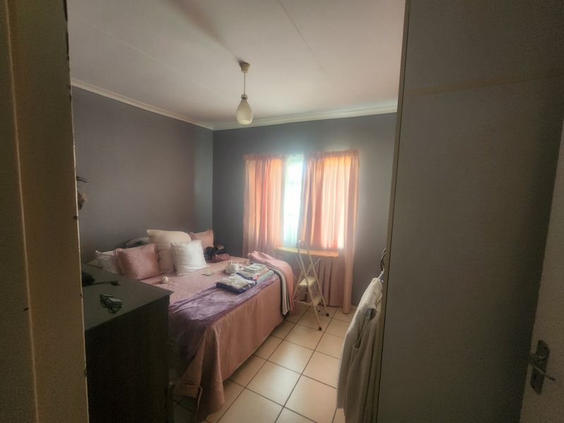 A standard bedroom featuring tiled flooring, coved ceilings, and built-in storage, offering a functional space with neutral wall tones.