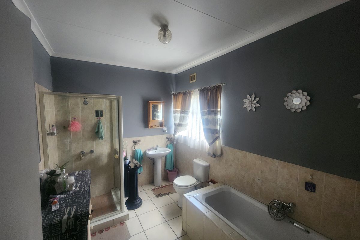 A functional bathroom featuring a shower enclosure, built-in bathtub, pedestal basin, and toilet with tiled finishes.