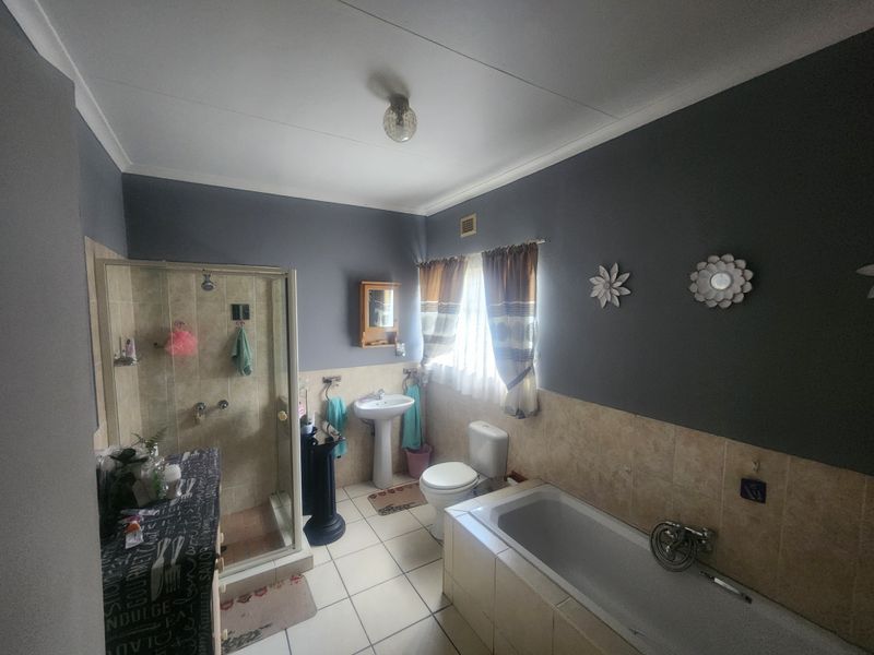 A functional bathroom featuring a shower enclosure, built-in bathtub, pedestal basin, and toilet with tiled finishes.