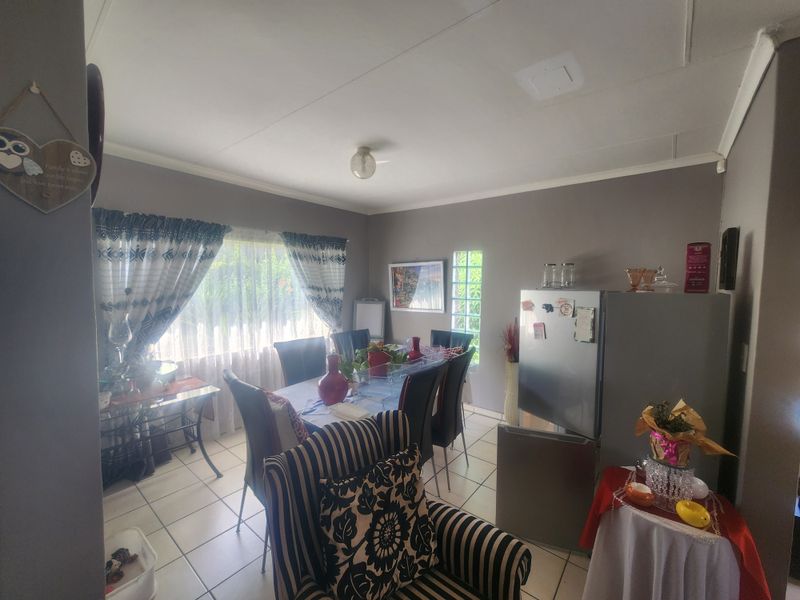 A dining area featuring tiled flooring, a glass block window feature, and neutral wall tones, providing a functional space for family meals.