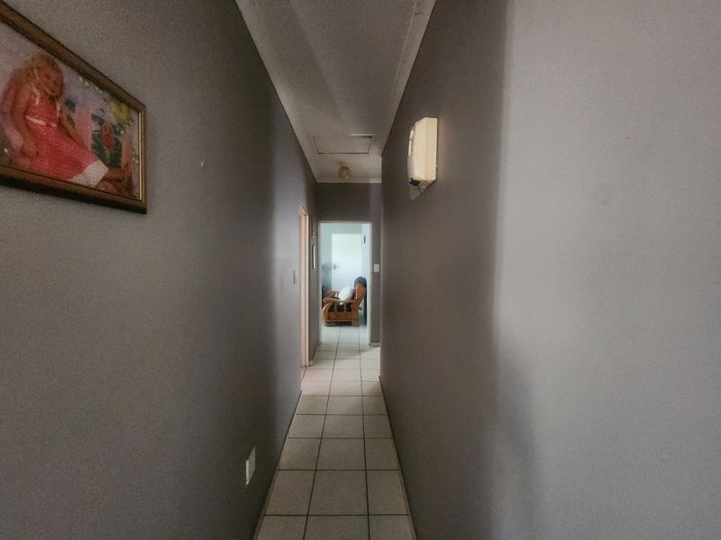 A functional hallway featuring tiled flooring and neutral wall finishes, providing access to adjacent rooms within the cottage.