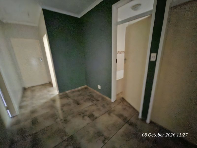A vacant hallway featuring tiled flooring and access to adjacent rooms, requiring cosmetic updates to improve the overall finish.
