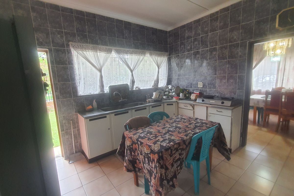 A functional kitchen featuring tiled walls, built-in cabinetry, and a stainless steel sink, with direct access to the exterior and adjacent dining area.