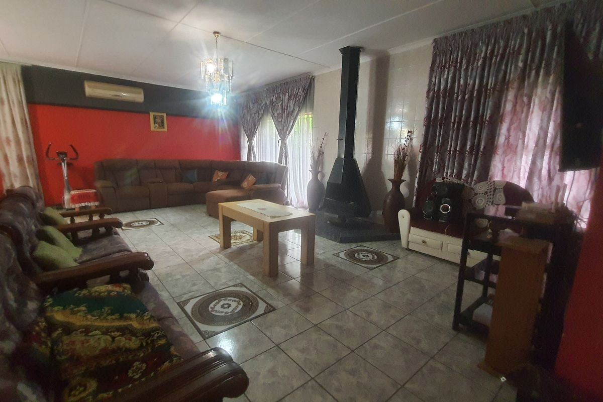 Spacious living room featuring a central freestanding fireplace, tiled flooring, and air conditioning unit.