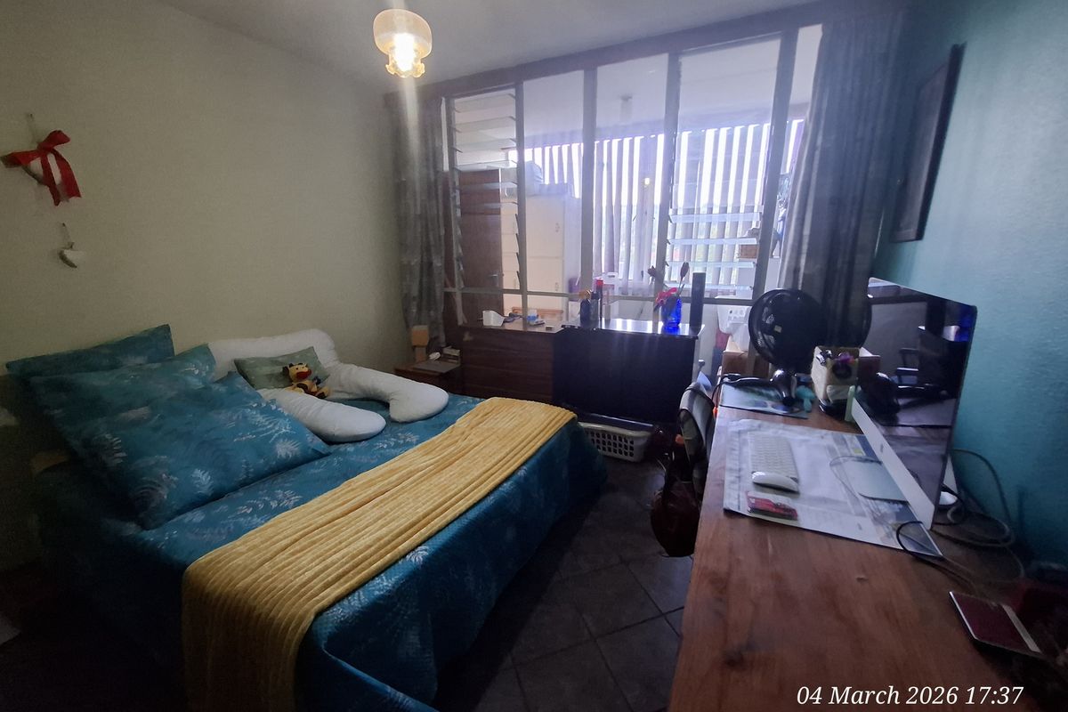 A bedroom featuring tiled flooring and a large glass partition wall leading to an adjacent space.