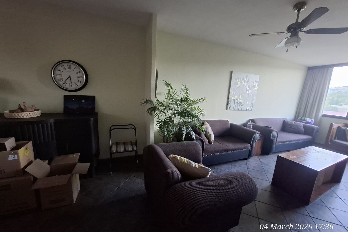 A spacious living area featuring tiled flooring and a ceiling fan, offering a comfortable layout with natural light from the window.