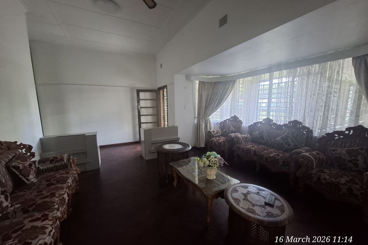 Spacious living room featuring large windows with natural light, neutral walls, and carpeted flooring.