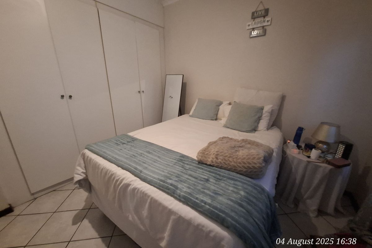 A bedroom featuring built-in cupboards and tiled flooring, providing a functional and comfortable living space.