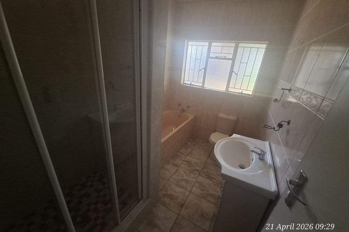 A functional bathroom featuring a shower enclosure, a bathtub, a pedestal basin, and a toilet with tiled walls and flooring.