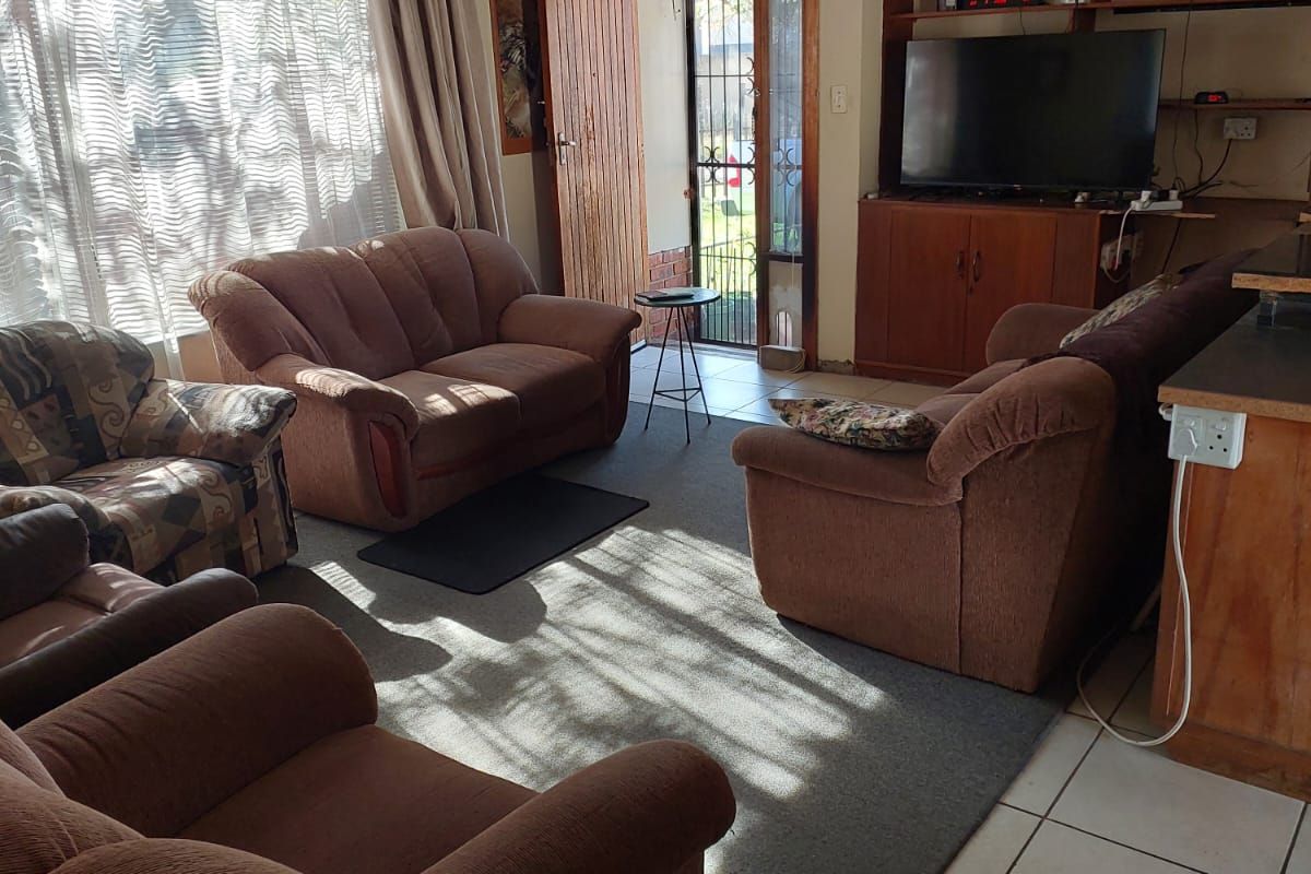 A living room featuring built-in wooden shelving, tiled flooring, and direct access to an outdoor area through a security gate.