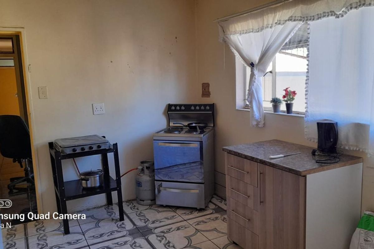 A compact kitchen area featuring a freestanding stove, a small base cabinet with countertop, and patterned floor tiles.