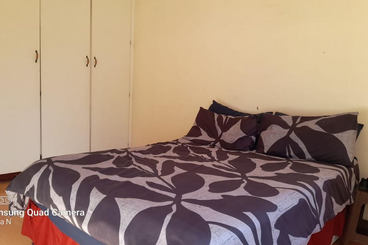 A bedroom featuring built-in cupboards with white doors and laminate flooring.