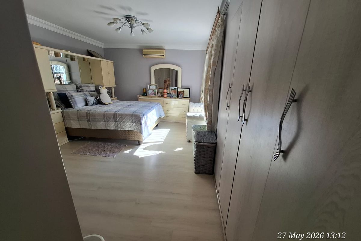 Spacious bedroom featuring light wood-look flooring, extensive built-in cabinetry, and a wall-mounted air conditioning unit.