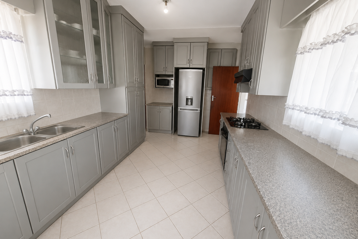 A well-maintained kitchen featuring grey shaker-style cabinetry, laminate countertops, a built-in gas hob, and tiled flooring, offering a clean and functional workspace.