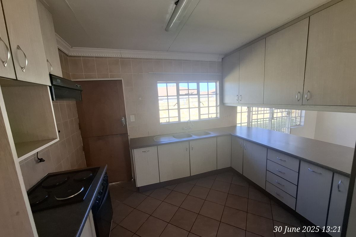 A functional kitchen featuring built-in cabinetry, laminate countertops, a double bowl sink, and an electric stove with an extractor fan.