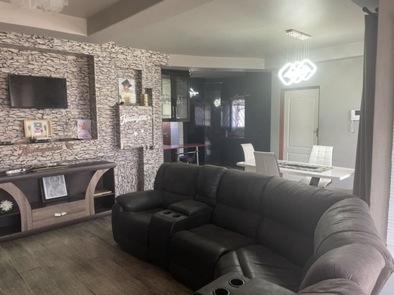 Open-plan living and dining area featuring a stone-clad feature wall, modern pendant lighting, and laminate flooring.