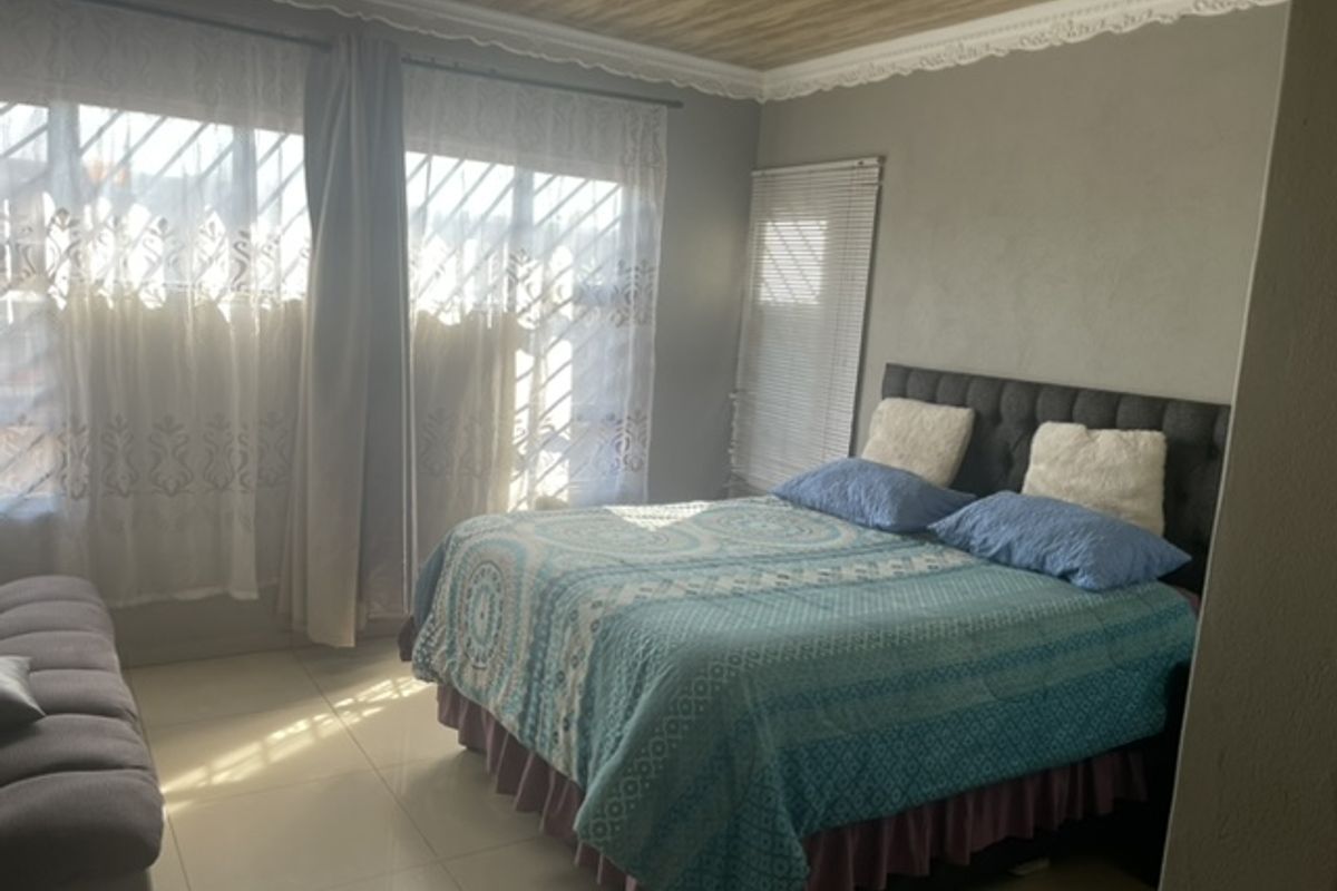 A bedroom featuring tiled flooring, decorative ceiling molding, and window security bars, providing a functional space with natural light.