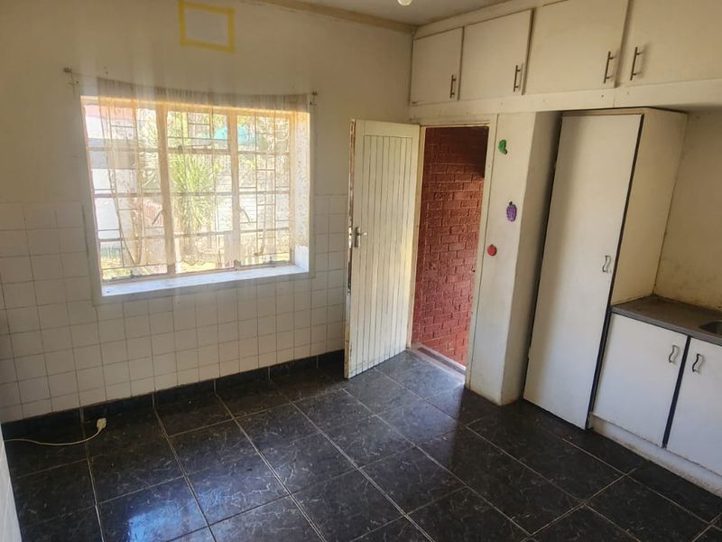 A functional, empty kitchen featuring built-in cabinetry, a double sink, and tiled flooring, offering a blank canvas for modern renovation and updates.