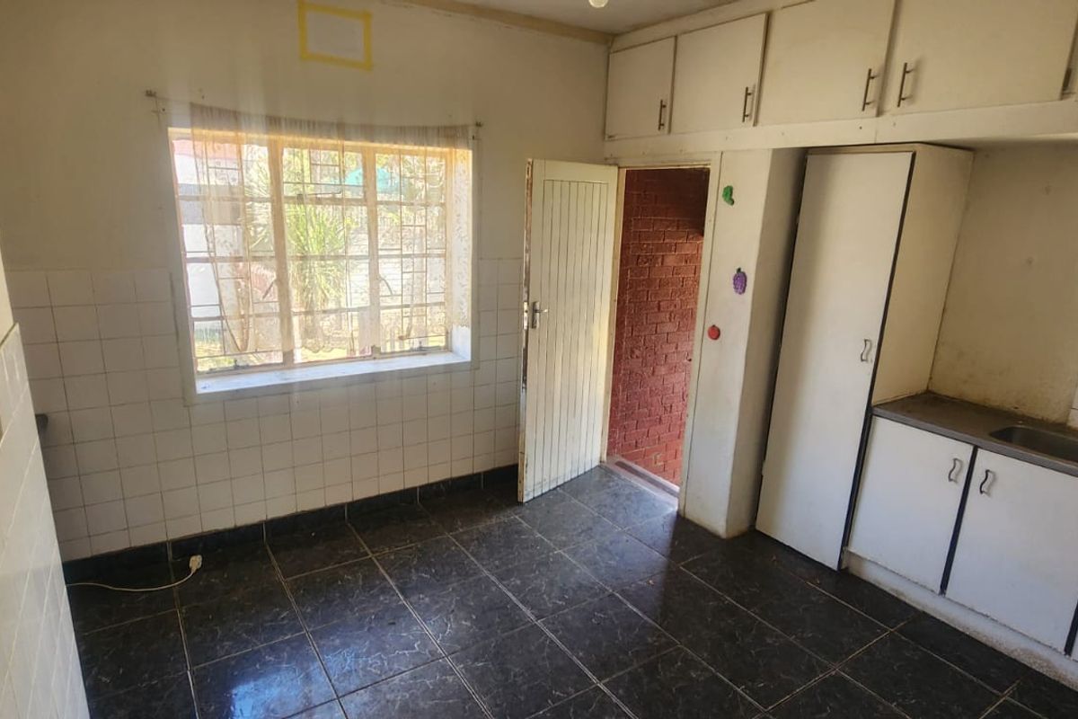 A functional, empty kitchen featuring built-in cabinetry, a double sink, and tiled flooring, offering a blank canvas for modern renovation and updates.