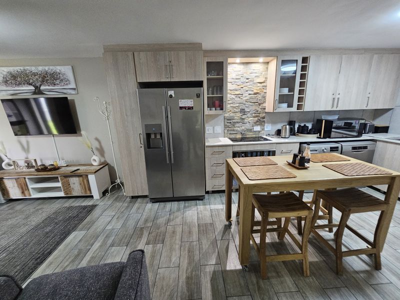 Modern open-plan kitchen featuring light wood cabinetry, stone veneer backsplash, and durable wood-look tile flooring, seamlessly integrated with the living area.