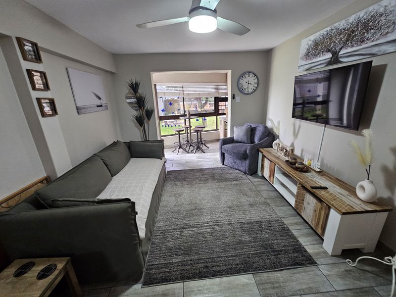 A comfortable living room featuring tiled flooring, a ceiling fan, and direct access to an adjoining patio area through a sliding door.