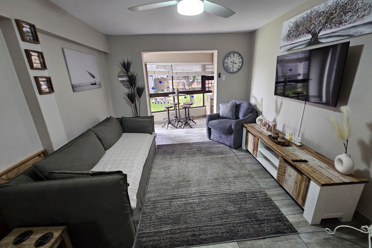 A comfortable living room featuring tiled flooring, a ceiling fan, and direct access to an adjoining patio area through a sliding door.
