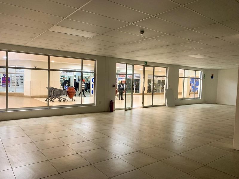 A vacant commercial retail space featuring large glass storefront windows, tiled flooring, and a suspended ceiling, suitable for a variety of business uses.