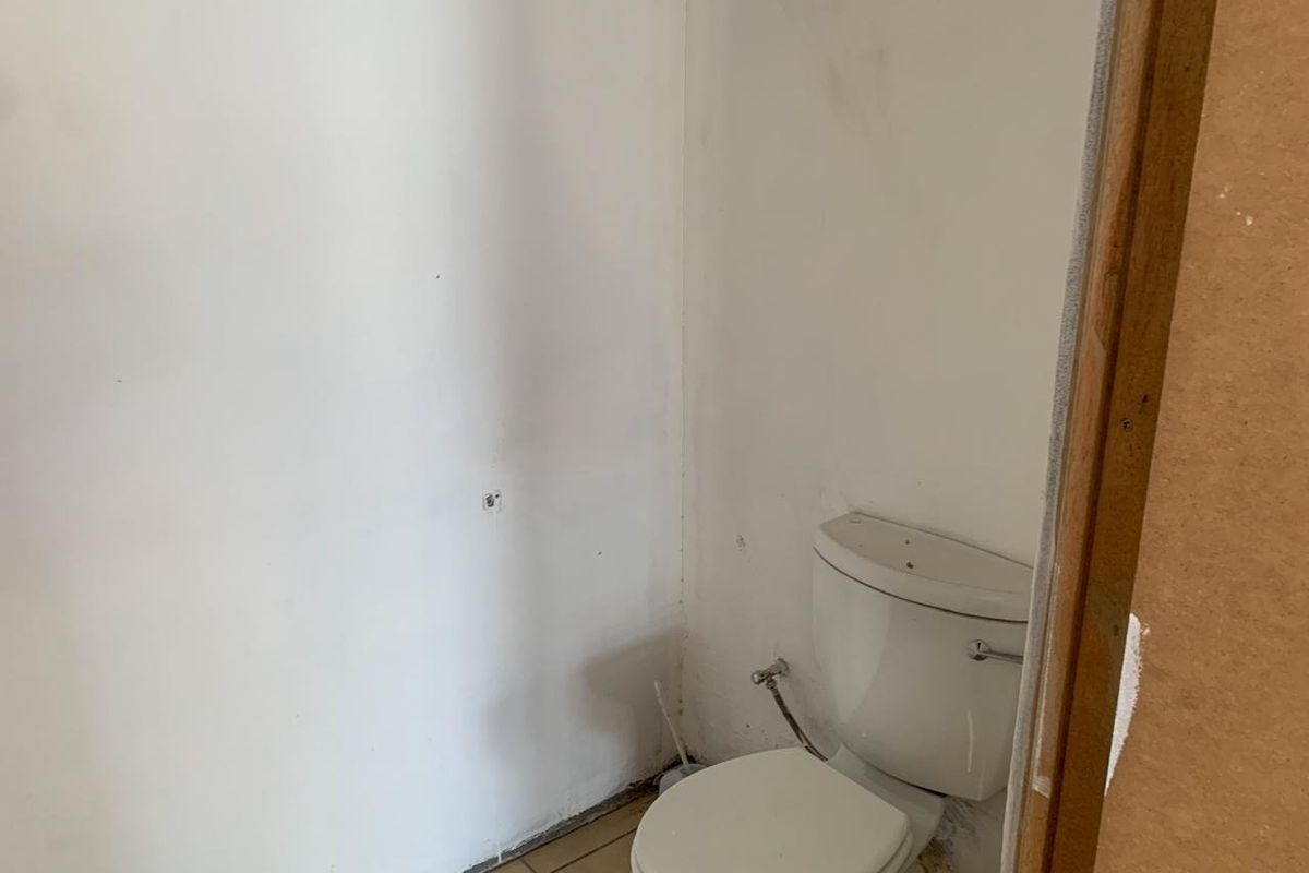 A small, unfinished bathroom space featuring a standard toilet, requiring cosmetic updates and wall finishing to complete the room.