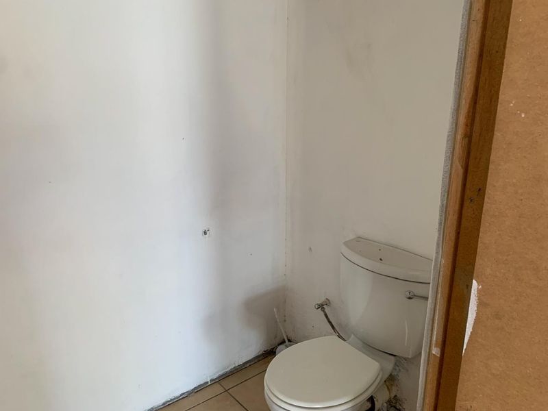 A small, unfinished bathroom space featuring a standard toilet, requiring cosmetic updates and wall finishing to complete the room.