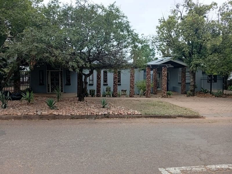 Front elevation of an office property featuring stone-clad pillars, a paved driveway, and established garden landscaping.