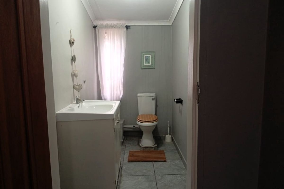 A functional bathroom featuring a vanity cabinet with basin, toilet, and tiled flooring, finished with neutral wall tones.