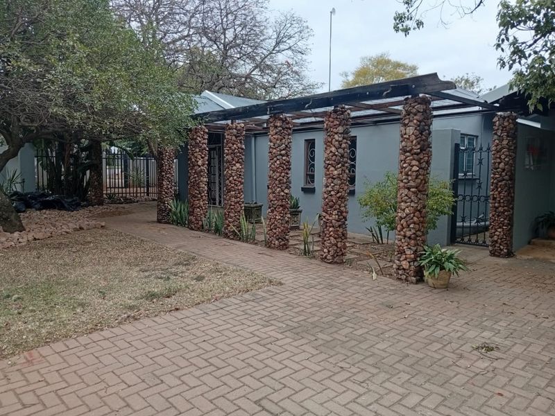 Front exterior view of the office property featuring a paved driveway, stone-clad pillars, and a timber pergola structure.
