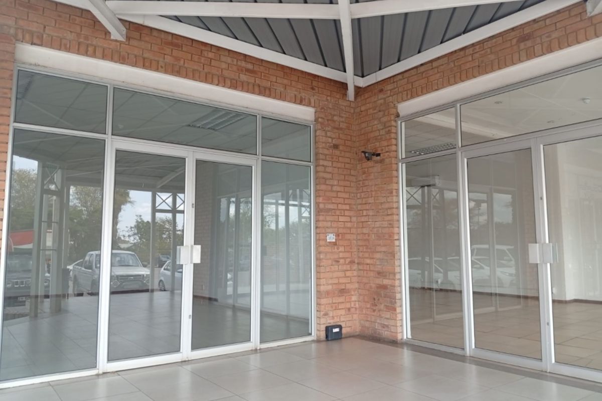 A modern retail storefront featuring an exposed brick facade, large aluminum-framed glass doors, and a clean tiled entrance area.