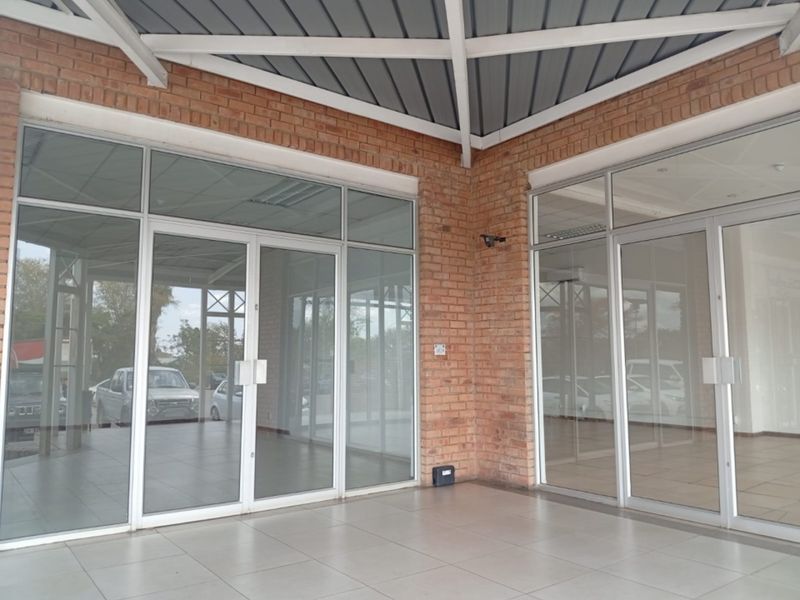 A modern retail storefront featuring an exposed brick facade, large aluminum-framed glass doors, and a clean tiled entrance area.