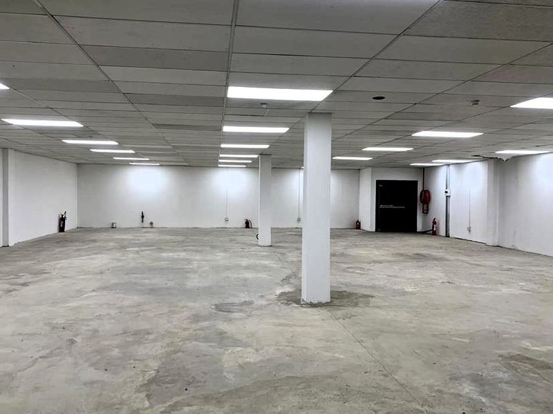 A large, open-plan retail or commercial space featuring a suspended ceiling, recessed lighting, and exposed concrete flooring, suitable for various business configurations.