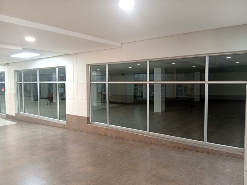 A vacant retail space featuring large glass storefront windows, tiled flooring, and recessed ceiling lighting, suitable for a variety of commercial uses.