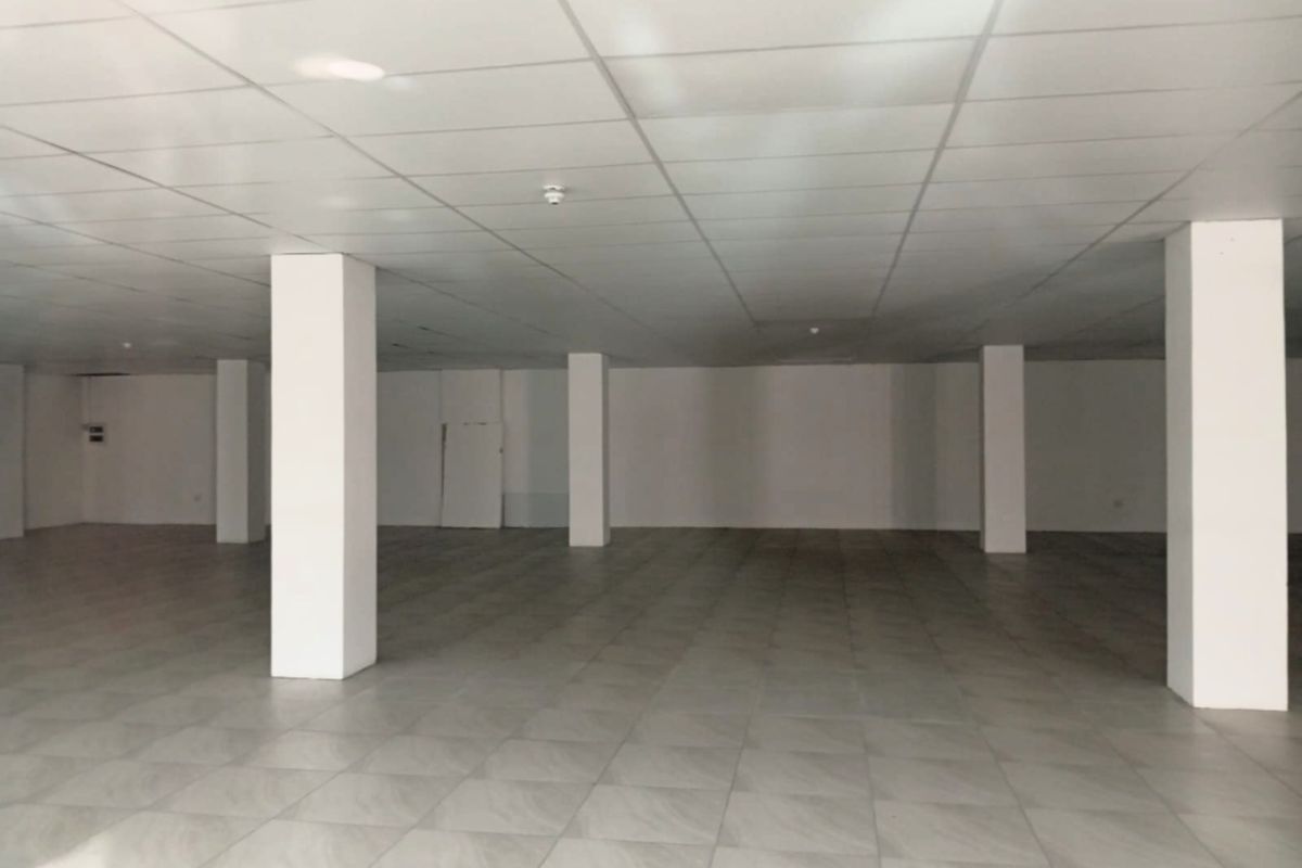 A spacious, open-plan retail area featuring a clean suspended ceiling, neutral tiled flooring, and structural support columns, ready for custom fit-out.