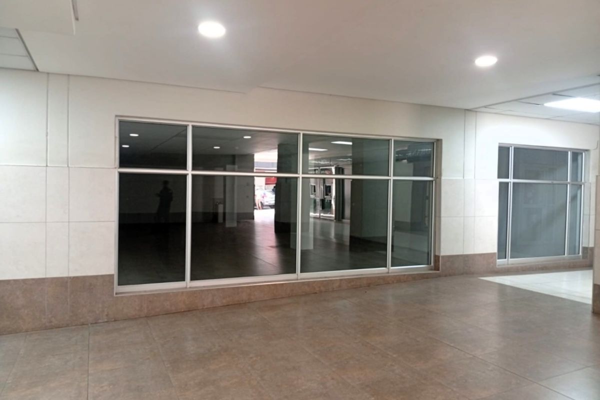 A vacant retail space featuring large glass storefront windows, recessed ceiling lighting, and neutral tiled flooring, suitable for various commercial business applications.