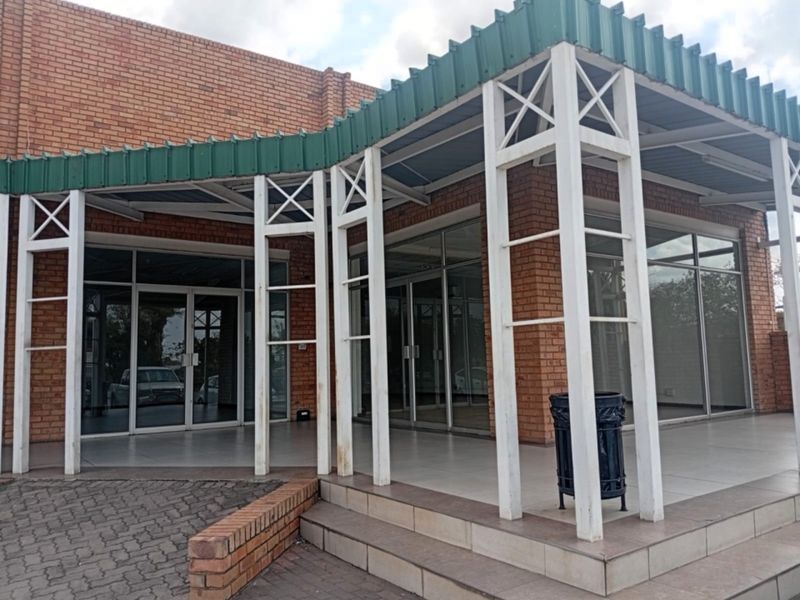 Front exterior view of a retail property featuring a brick facade, covered patio area, and large glass storefront entrance doors.